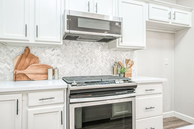 kitchen featuring baseboards, white cabinets, decorative backsplash, light stone countertops, and stainless steel appliances