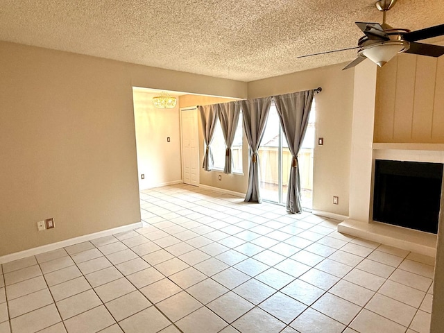 unfurnished living room with a fireplace with raised hearth, ceiling fan, light tile patterned floors, a textured ceiling, and baseboards