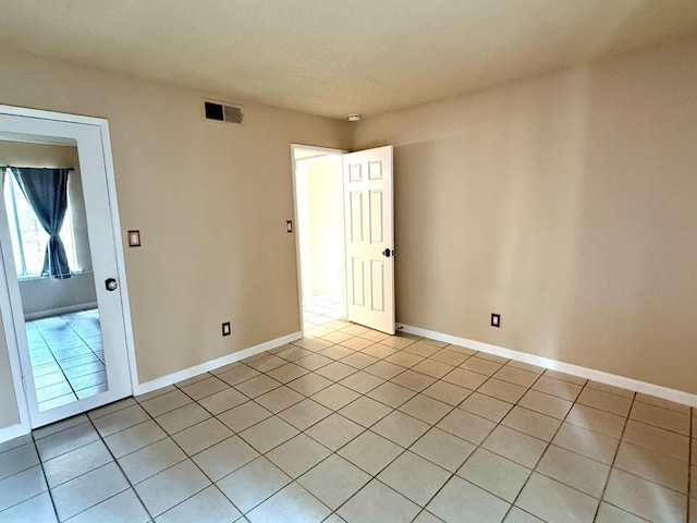 empty room featuring light tile patterned flooring, visible vents, and baseboards