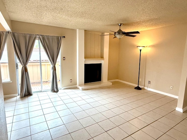 unfurnished living room featuring a large fireplace, ceiling fan, baseboards, and light tile patterned flooring