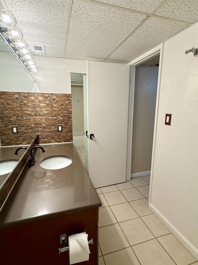 bathroom featuring a paneled ceiling, tile patterned flooring, baseboards, and vanity