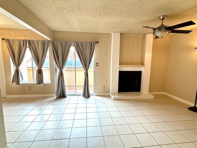 unfurnished living room featuring baseboards, a fireplace with raised hearth, a ceiling fan, a textured ceiling, and light tile patterned flooring