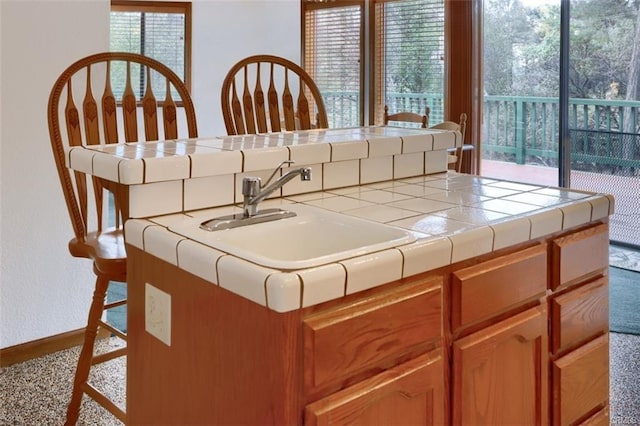 kitchen with tile countertops, a sink, and baseboards