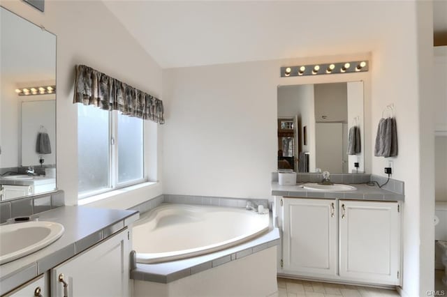 bathroom featuring lofted ceiling, two vanities, a sink, and a bath