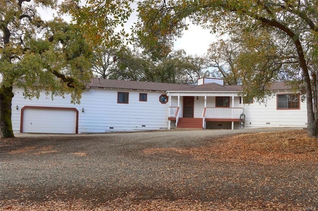 ranch-style home with crawl space, covered porch, a garage, and gravel driveway