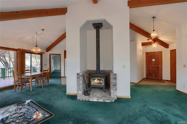 unfurnished living room featuring a wood stove, carpet, baseboards, and beamed ceiling