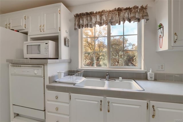 kitchen featuring white appliances, white cabinets, a sink, and light countertops