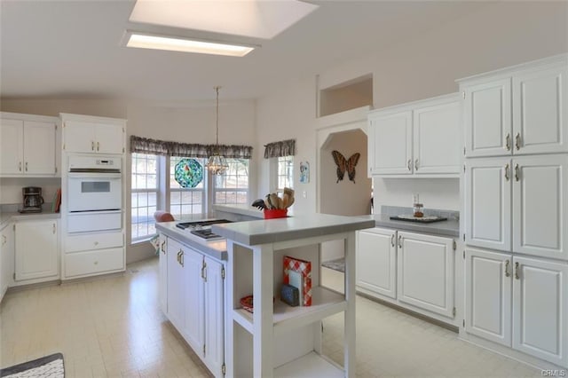 kitchen with a warming drawer, open shelves, white oven, and white cabinets