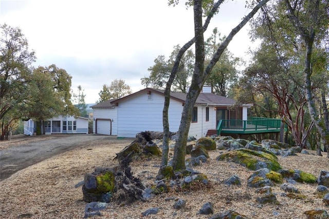 exterior space featuring driveway, an attached garage, and a deck