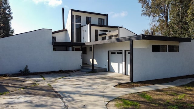 rear view of house with concrete driveway and stucco siding