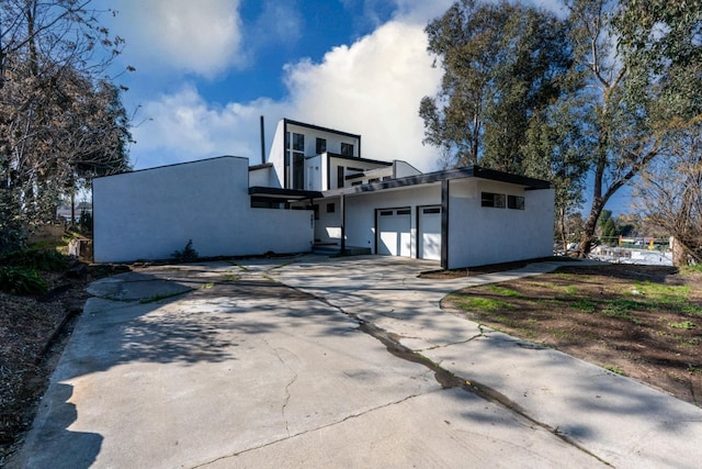 view of side of home with a garage, driveway, and stucco siding