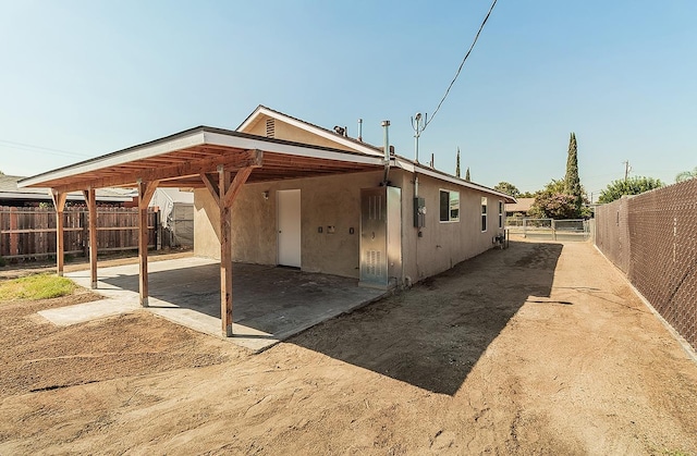 exterior space featuring a carport, fence, and stucco siding