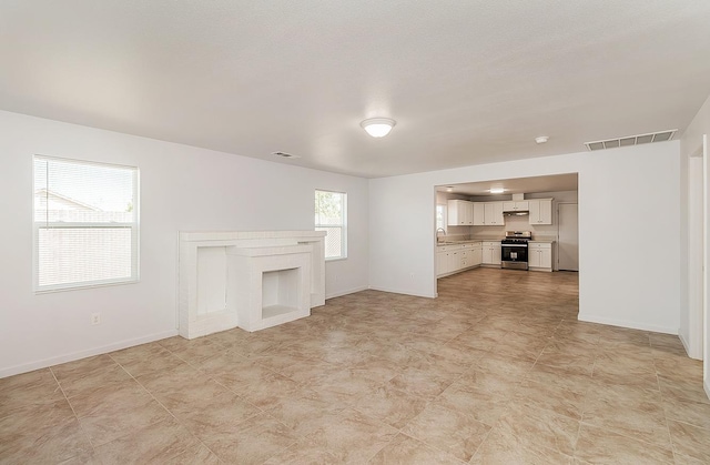 unfurnished living room featuring baseboards, a fireplace, and visible vents