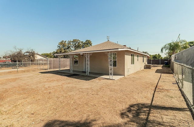 back of property featuring a patio, stucco siding, a shingled roof, central AC, and a fenced backyard