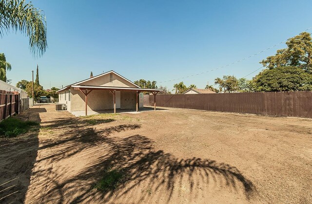 view of yard featuring a carport, a fenced backyard, and central AC