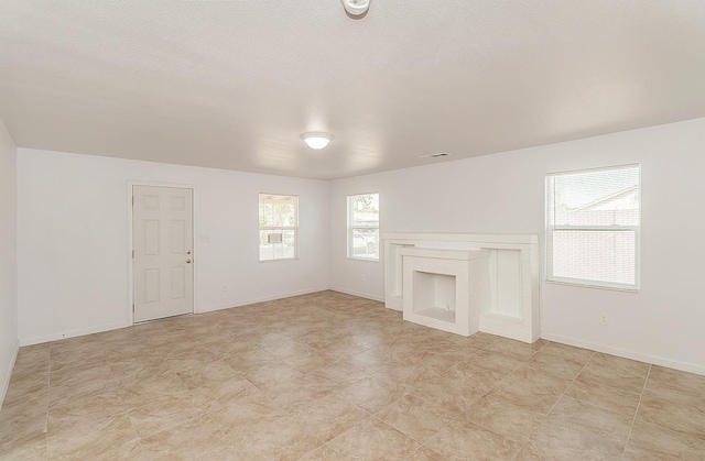 unfurnished living room with visible vents, a fireplace, and baseboards