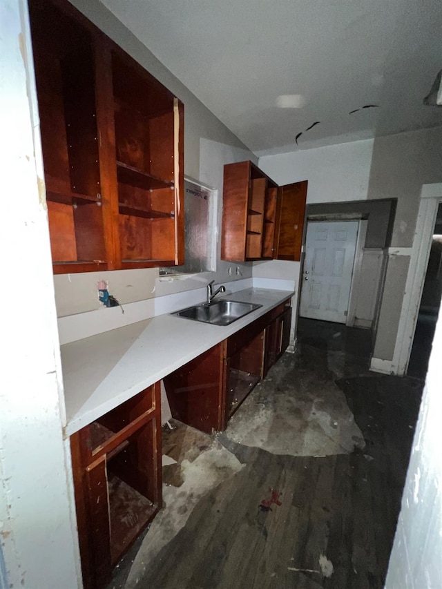 kitchen featuring dark wood-style floors, brown cabinets, light countertops, open shelves, and a sink