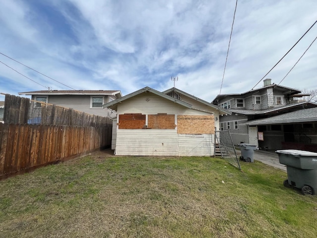 rear view of property featuring a lawn and fence