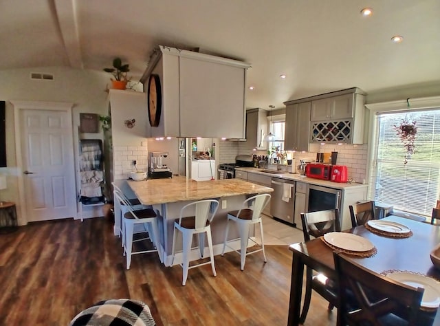 kitchen with visible vents, a breakfast bar area, a peninsula, stainless steel appliances, and backsplash