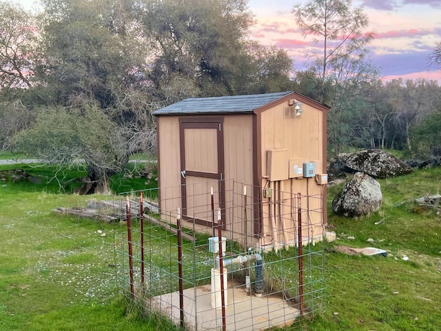 outdoor structure at dusk with an outbuilding, a yard, and a storage shed