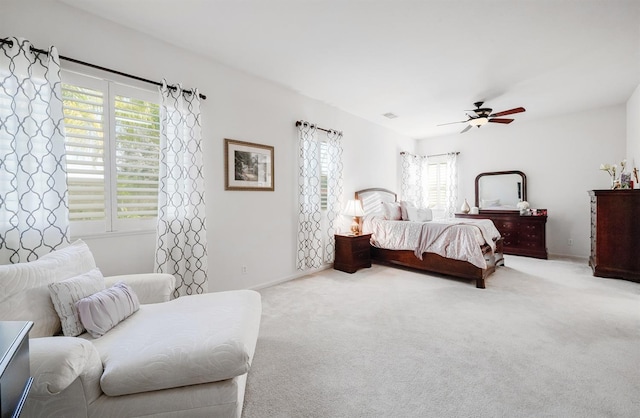 carpeted bedroom featuring visible vents, multiple windows, and a ceiling fan