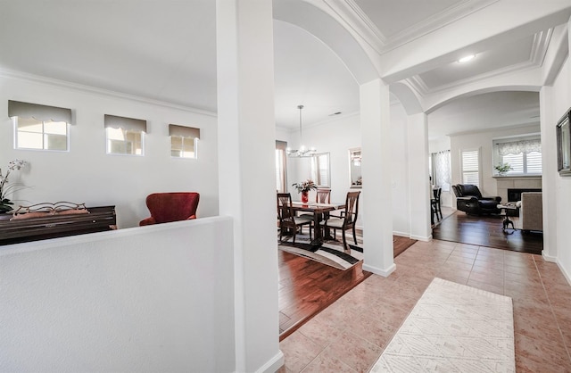 foyer entrance with a chandelier, arched walkways, ornamental molding, and tile patterned flooring