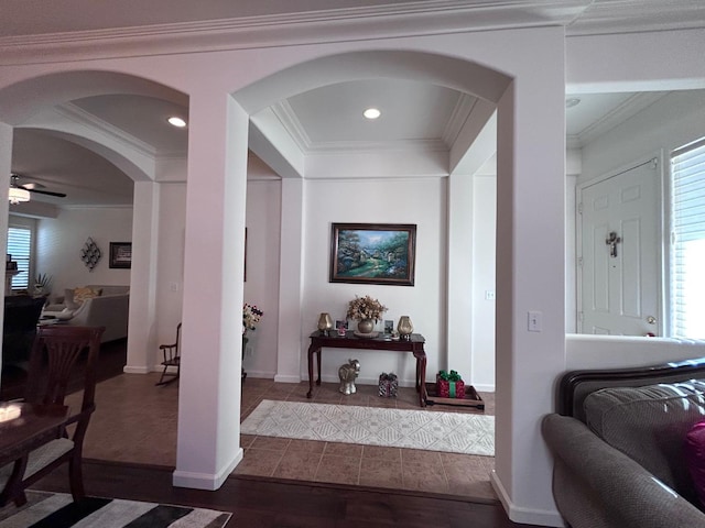 hallway with ornamental molding, arched walkways, baseboards, and wood finished floors