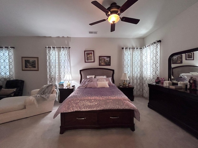 bedroom with visible vents, a ceiling fan, and light colored carpet