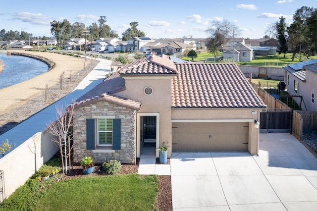 mediterranean / spanish house with an attached garage, fence, concrete driveway, a residential view, and stucco siding