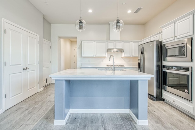 kitchen featuring appliances with stainless steel finishes, light wood-type flooring, light countertops, and under cabinet range hood