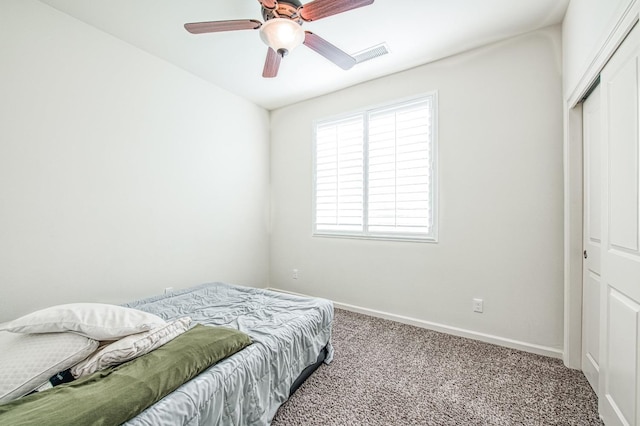 carpeted bedroom with a ceiling fan, visible vents, baseboards, and a closet