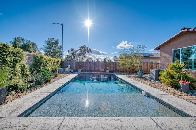 view of swimming pool featuring a fenced backyard, a fenced in pool, and central air condition unit