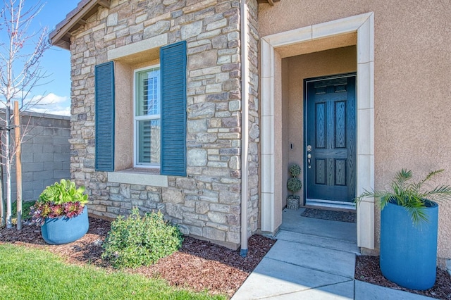 property entrance featuring stone siding and stucco siding