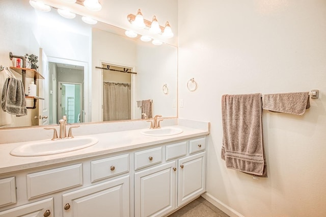 full bathroom featuring double vanity, baseboards, and a sink