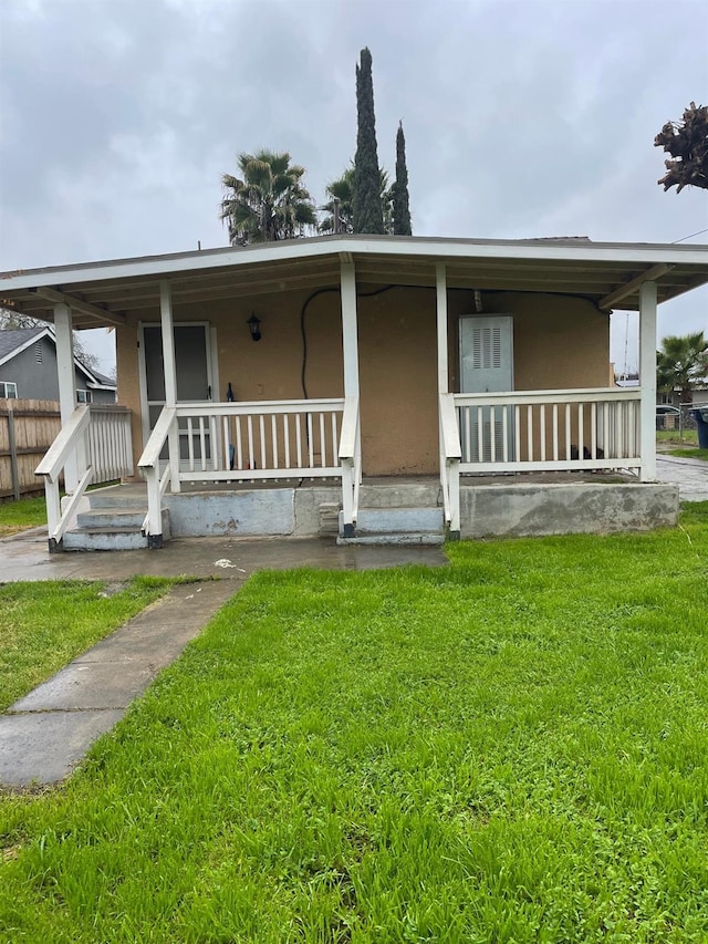 view of front of house with a porch, a front yard, and stucco siding