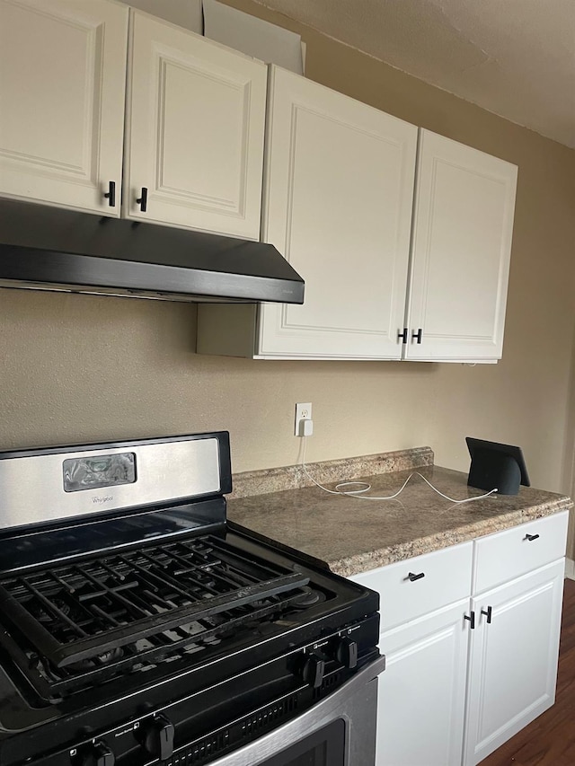 kitchen featuring gas stove, exhaust hood, and white cabinets