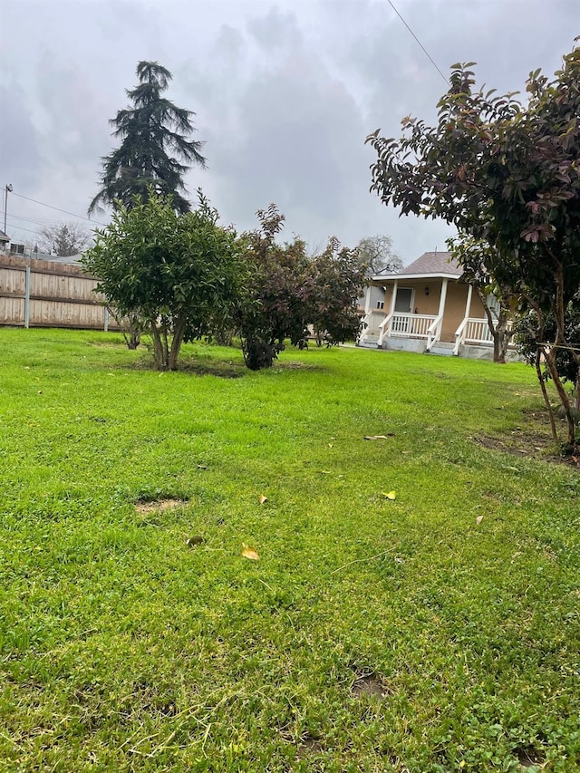 view of yard with covered porch and fence