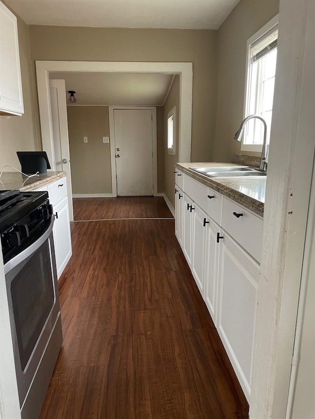 kitchen with dark wood finished floors, a sink, gas range, and white cabinets