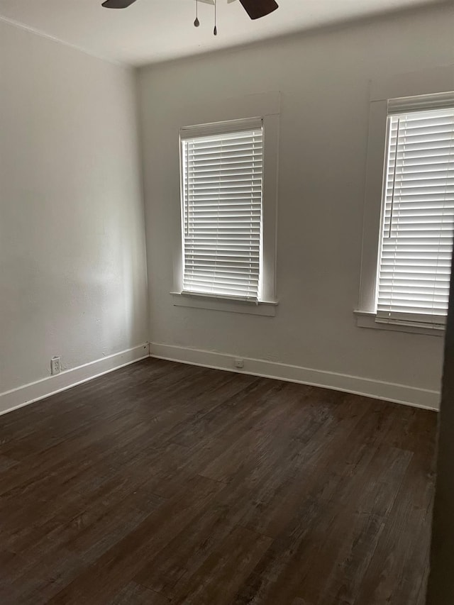 unfurnished room with dark wood-style floors, ceiling fan, and baseboards