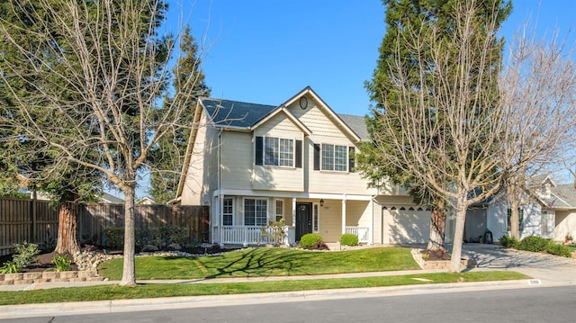 traditional-style home featuring a porch, fence, a garage, driveway, and a front lawn