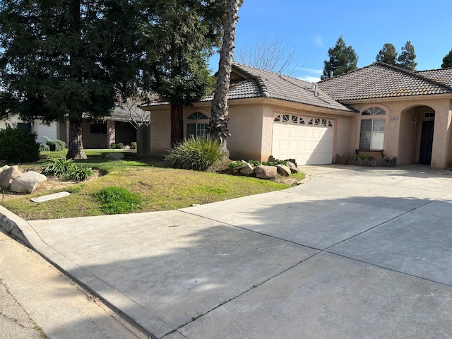 view of front of home featuring an attached garage, a tiled roof, concrete driveway, and stucco siding