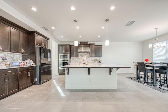 kitchen with stainless steel appliances, visible vents, a kitchen breakfast bar, dark brown cabinets, and wall chimney exhaust hood