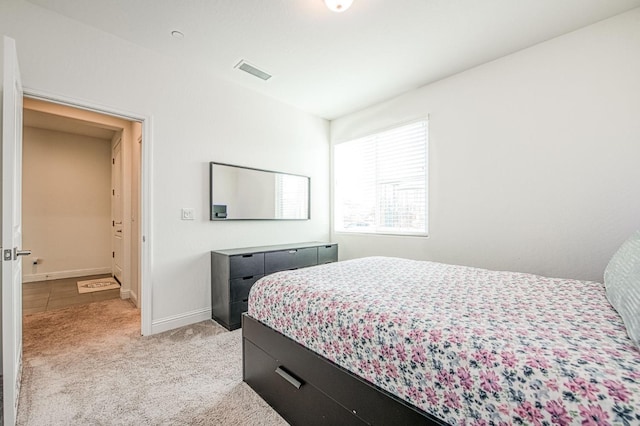 bedroom with visible vents, light carpet, and baseboards