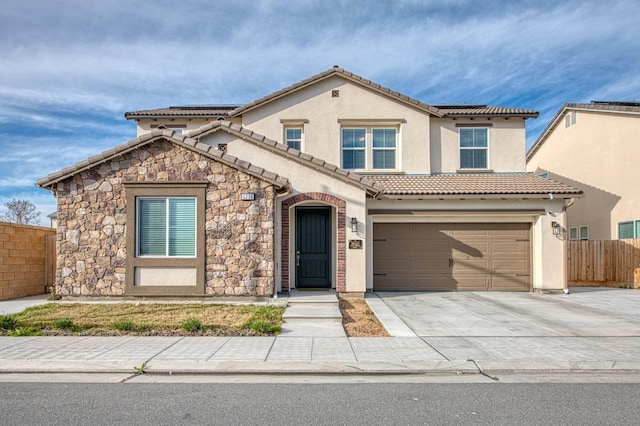 view of front of house with driveway, stone siding, a tile roof, fence, and stucco siding