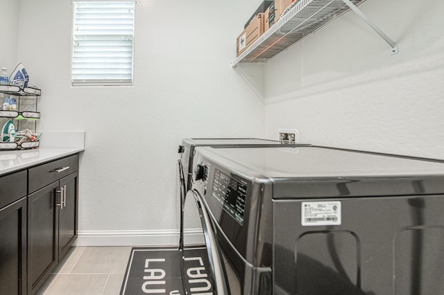 laundry area with cabinet space, washer and clothes dryer, baseboards, and light tile patterned floors