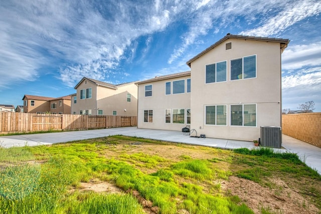 back of property with a fenced backyard, central AC unit, a patio, and stucco siding