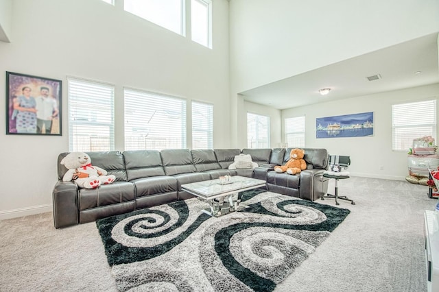 carpeted living room with a wealth of natural light, a high ceiling, and baseboards