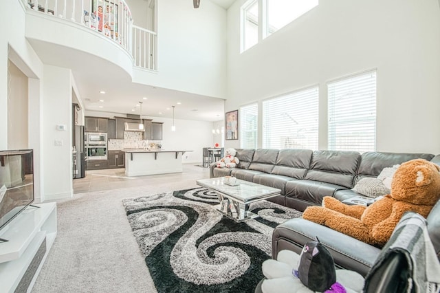 living room featuring a high ceiling, light carpet, baseboards, and recessed lighting