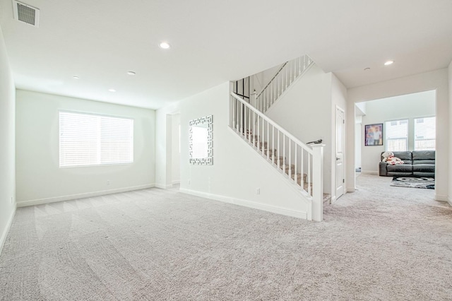 carpeted spare room featuring recessed lighting, visible vents, stairway, and baseboards