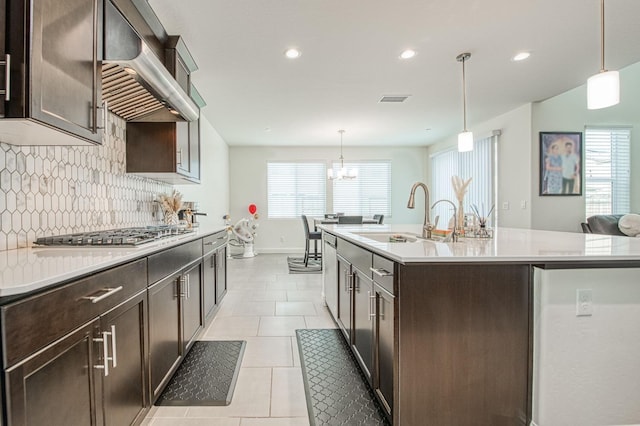 kitchen with dark brown cabinetry, a sink, visible vents, wall chimney exhaust hood, and stainless steel gas stovetop